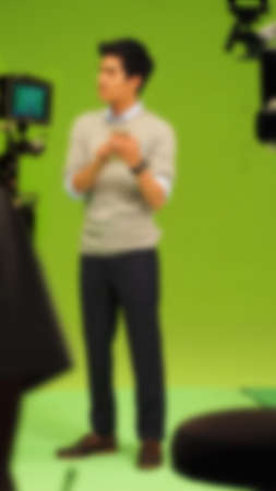 Blurry images of making TV commercial movie video in big green screen background. Film crew team working with actor. Recording by professional digital camera and lighting set. film behind the scenesの写真素材