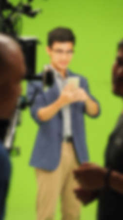 Blurry images of making TV commercial movie video in big green screen background. Film crew team working with actor. Recording by professional digital camera and lighting set. film behind the scenesの写真素材