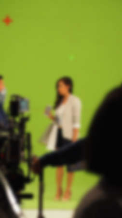 Blurry images of making TV commercial movie video in big green screen background. Film crew team working with actor. Recording by professional digital camera and lighting set. film behind the scenesの写真素材