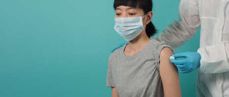 Vaccination immunization disease prevention concept. Woman in medical face mask getting Covid 19 or...