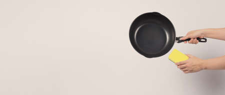 Cleaning Electric non stick pan. Hand on white background cleaning the non stick pan with handy dish washing sponge which yellow color on the soft side and green on hard side for hygiene after cook.の写真素材