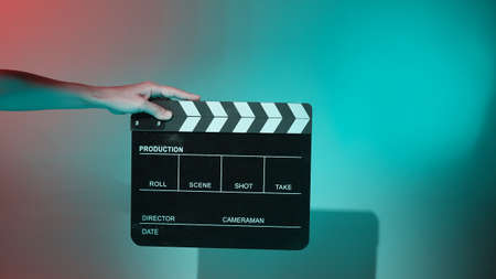 Blurry images of movie slate or clapper board. Hand holds empty film making clapperboard on color background in studio for film movie shooting or recording.の写真素材