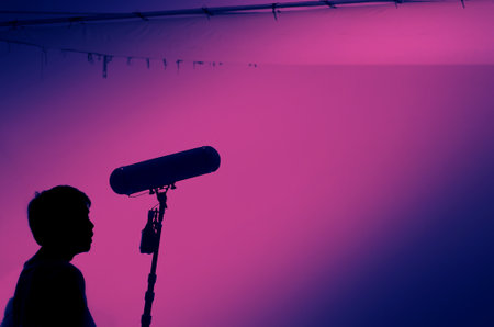 Boom Microphone for sound recording in film industry. Sound boom operator recording sound by microphone fisher for movie set in studio. Boom mic holds up high by video or film production crew team manの写真素材