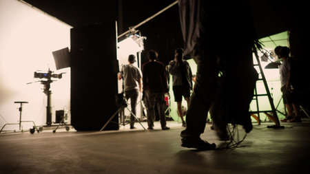 Blurry images of film crew working and filming in video production studio which using equipments such as cinema camera big film light and soft box or light diffusion panel. TV Commercial Film industryの写真素材
