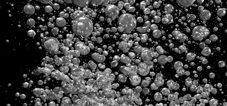 Soda water bubbles splashing underwater against black background. Cola liquid texture that fizzing...