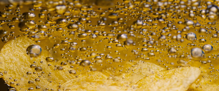 Deep fried potato chips under golden oil water. Frying rounded potatoes chip with hot boiling oil...