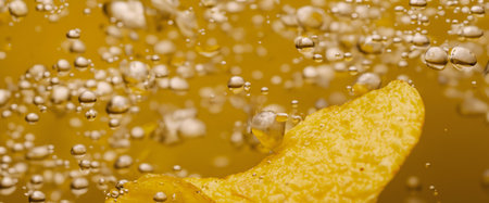 Deep fried potato chips under golden oil water. Frying rounded potatoes chip with hot boiling oil...