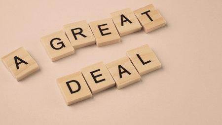 Word of A Great Deal. Text written by wood toy or wood cubes on white paper background with texture. Top view of wooden english alphabet arranging to words. Close up of photo letter design wood toys.の写真素材