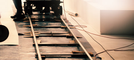 Camera trolley or camera dolly cart rails for filmmaking on studio shooting set. Pro videographer dolly rail track for filming movie mounted on studio floor. Video production dolly and crews in set.の写真素材