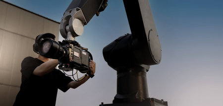 Video or film production with high tech robotic arm equipped with a professional cinema camera. Operated by a cinematographer. Advanced motion control system enables precise camera movements filming.の写真素材