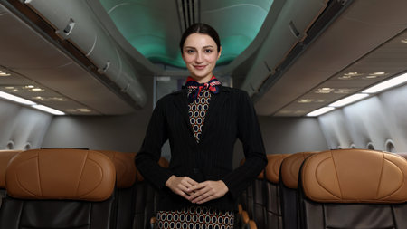 Flight attendant or Air Hostess. A friendly flight attendant stand confidently inside an airplane cabin. Professional hospitality and elegant uniform. Aviation service travel airline Flight attendant.の写真素材