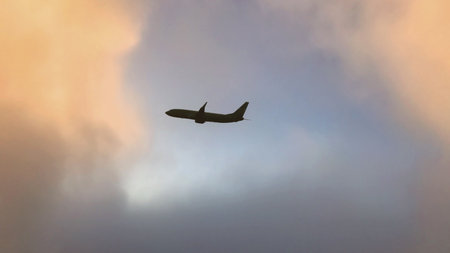 Airplane in the sky. Airplane in flight at sunset or evening sky. Commercial airliner silhouette in the colorful evening or night moon skies. Aircraft symbol of travel adventure global connectivity.の写真素材