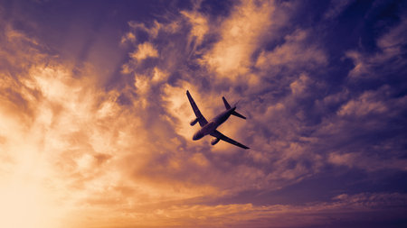 Airplane in the sky. Airplane in flight at sunset or evening sky. Commercial airliner silhouette in the colorful evening or night moon skies. Aircraft symbol of travel adventure global connectivity.の写真素材