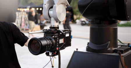 Behind the scenes of movie shooting or video production and film crew team with camera equipment at outdoor location. Video camera with professional robotic arm. BTS of Filming camera setup at outdoorの写真素材