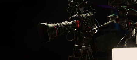 Behind the scenes of movie shooting or filming or video production with high quality camera and tripod equipment set up and professional film crew team in studio lighting. Video production camera gearの写真素材