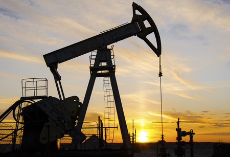 Pump jack silhouette during sunset on the oilfield. Oil and gas concept.の写真素材