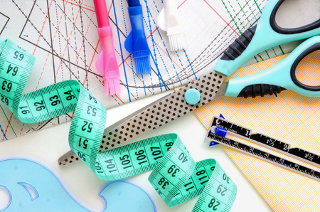Sewing kit on the background of the pattern and scaled paper. Colorful set consisting of scissors, cutter?s ruler, pencils and measuring tape.の写真素材