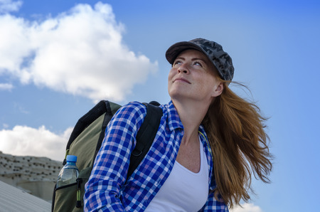 Young beautiful woman backpacker with red hair and freckles traveling in the desert. Sandy dunes and blue sky on sunny summer day. Travel, adventure, freedom concept. Toned.の写真素材