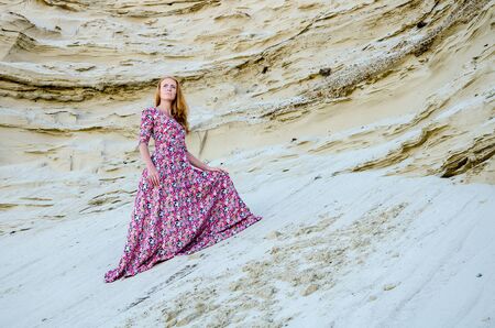 Beautiful slim young girl wearing long colorful dress in the desert. Fashion and glamour concept. Toned.の写真素材
