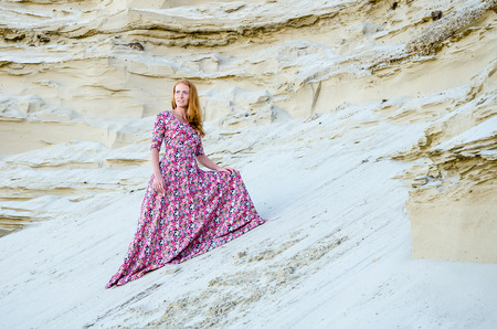 Beautiful slim young girl wearing long colorful dress in the desert. Fashion and glamour concept. Toned.の写真素材