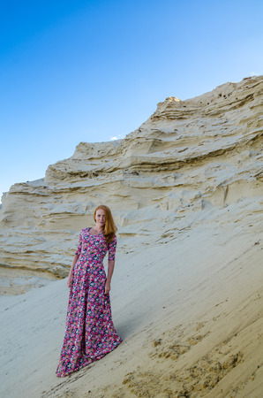 Beautiful slim young girl wearing long colorful dress in the desert. Fashion and glamour concept. Toned.の写真素材