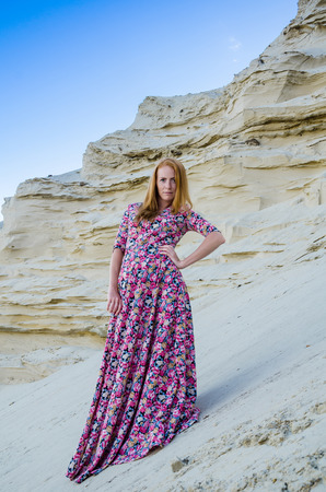 Beautiful slim young girl wearing long colorful dress in the desert. Fashion and glamour concept. Toned.の写真素材