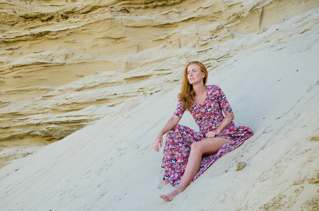 Beautiful slim young girl wearing long colorful dress in the desert. Fashion and glamour concept. Toned.の写真素材