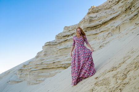 Beautiful slim young girl wearing long colorful dress in the desert. Fashion and glamour concept. Toned.の写真素材