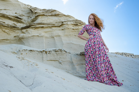 Beautiful slim young girl wearing long colorful dress in the desert. Fashion and glamour concept. Toned.の写真素材