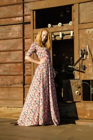 Young beautiful girl wearing long dress on the the background of old ship.の写真素材