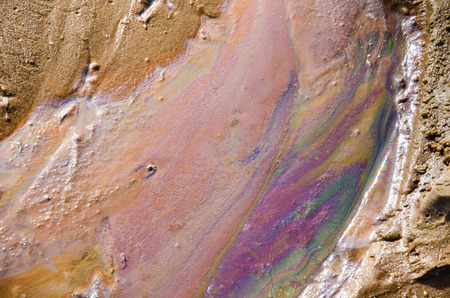 Rainbow oil slick on the sand. Textured background. Pollution of water and ground concept.の写真素材