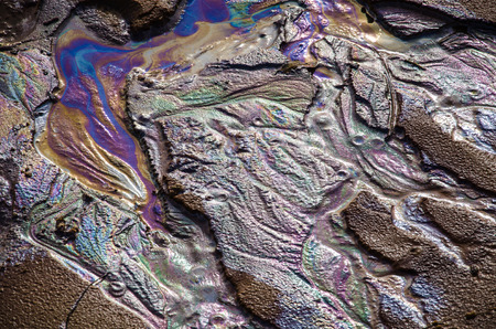 Rainbow oil slick on the sand. Textured background. Pollution of water and ground concept.の写真素材