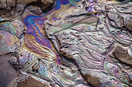 Rainbow oil slick on the sand. Textured background. Pollution of water and ground concept.の写真素材
