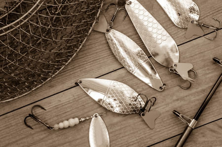 Fishing accessories for summer. Tackle, bait, lure, jig, hook, net. Wooden background. Outdoor...