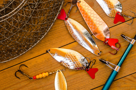 Fishing accessories for summer. Tackle, bait, lure, jig, hook, net. Wooden background. Outdoor activity and leisure concept.の写真素材