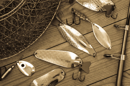 Fishing accessories for summer. Tackle, bait, lure, jig, hook, net. Wooden background. Outdoor activity and leisure concept. Toned.の写真素材