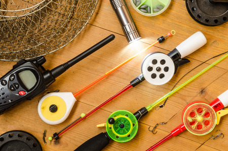 Fishing accessories  consisting of tackles, radio, weights, hook, flashlight, net. Wooden background. Outdoor activity and leisure concept.の写真素材