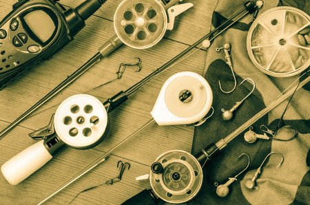 Fishing accessories  consisting of tackles, radio, weights, hook, net. Wooden background. Outdoor activity and leisure concept. Toned.の写真素材