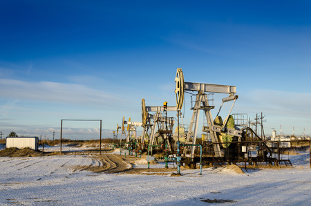 Group of oil pumps and wellheads in the oilfield during winter. Oil and gas concept.の写真素材