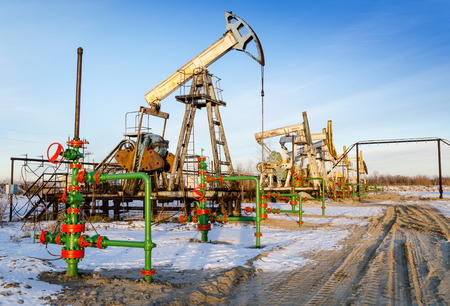 Group of oil pumps and wellheads in the oilfield during winter. Oil and gas concept.の写真素材