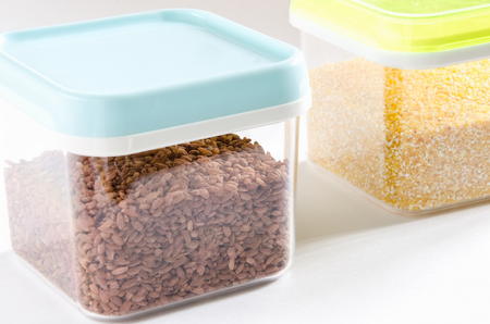 Food storage. Food ingredients (brown rice and polenta) in plastic containers. Selective focus.の写真素材