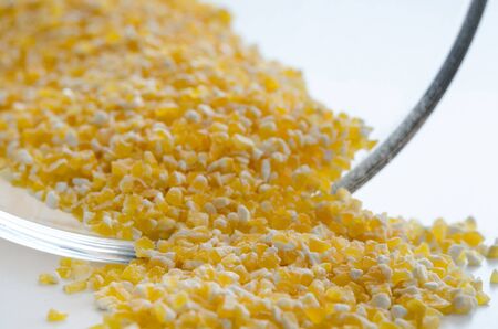Pile of the uncooked raw polenta near glass bowl. Healthy lifestyle concept. Closeup macro shot.の写真素材
