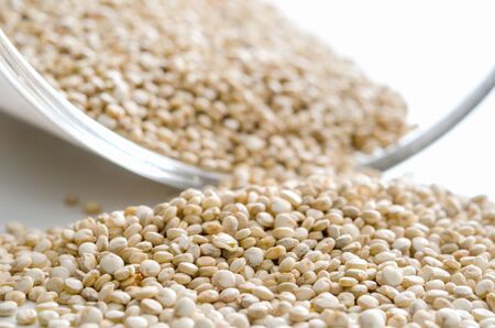 Pile of the uncooked raw quinoa near glass bowl. Healthy lifestyle concept. Closeup macro shot.の写真素材