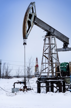 Pump jack and wellhead in the oilfield. Rig at the background. Oil and gas concept.の写真素材