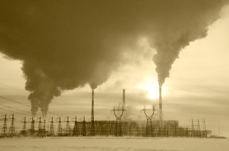 Gas power plant in cold winter landscape during sunset. Pipes with smoke. Power transmission tower foreground. Energy industry concept. Toned.の写真素材