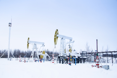 Group of oil pumps and wellheads in the oilfield during winter. Oil and gas concept.の写真素材