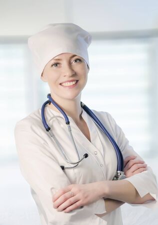 Young woman medical doctor portrait in white coat and cap with stethoscope.の写真素材