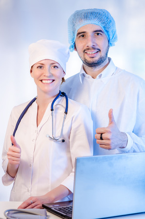 Group portrait of medical doctors in hospital looking at camera and smiling. Man wearing surgeon coat and woman wearing white cap. Focus on woman doctor.の写真素材