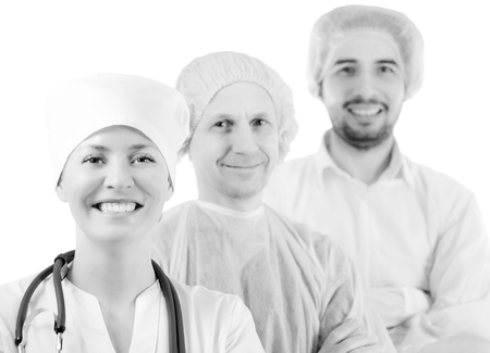 Group portrait of medical doctors in hospital, looking at camera and smiling isolated on white background. Two men wearing surgeon coat and woman wearing white cap and coat. Focus on woman doctor.の写真素材