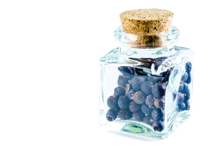 Dry juniper berries in glass bottle isolated on white background. Closeup macro shot.の写真素材